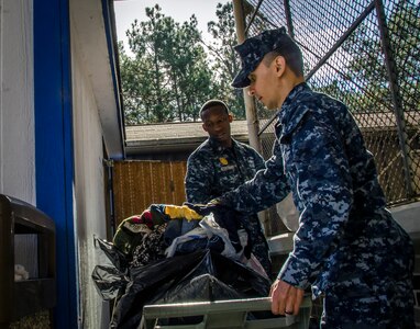OS1 Strowder and FC1 Byrd, both assigned to the Naval Consolidated Brig Charleston, volunteer their time at Castaways Thrift Shop, Dec. 18, 2014, at Joint Base Charleston - Weapons Station, S.C. The volunteer opportunity was in accordance with CPO 365, a year-round training initiative that Chiefs Messes throughout the Navy take on to prepare first class petty officers to become chiefs. (U.S. Air Force Photo / Senior Airman Tom Brading)