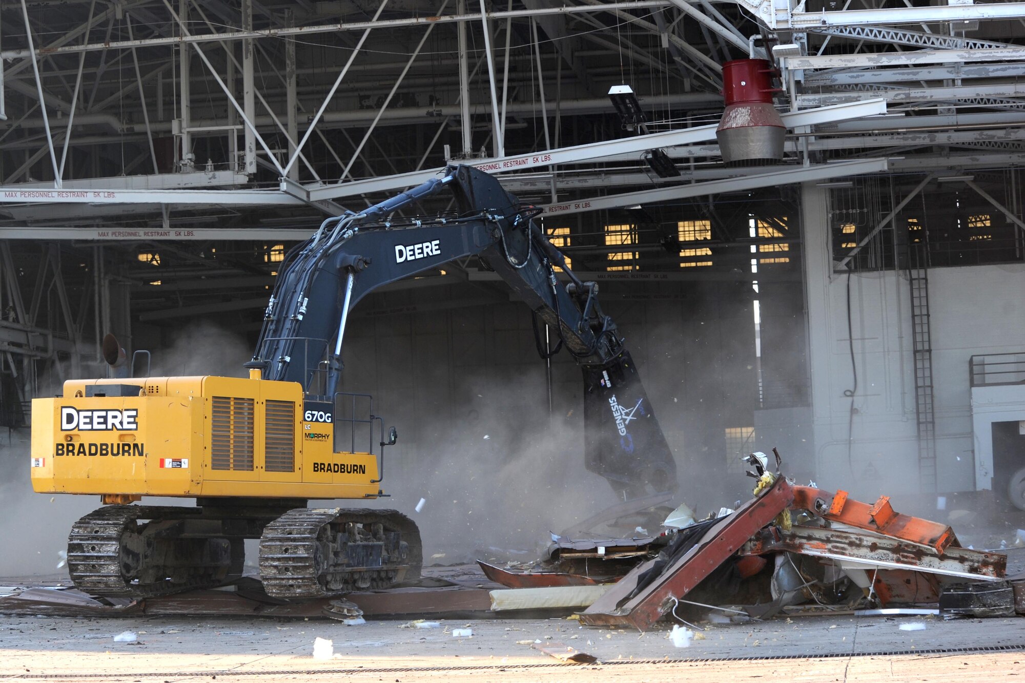 A hydraulic excavator tears down a hangar door as part of on-going construction work, Dec. 9, at McConnell Air Force Base, Kan. The Department of Defense mandates that 60 percent of all construction debris be recycled. In 2014, McConnell recycled more than 78,000 tons of construction material. (U.S. Air Force photo/Airman 1st Class David Bernal Del Agua)