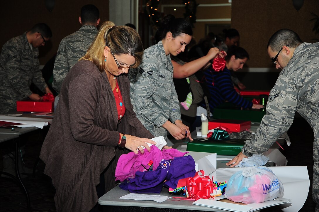 Airmen and local volunteers wrap presents during the Happy Fund Shop and Wrap event Dec. 18 in the Columbus Club. The event helped 350 underprivileged children from the local area receive clothing and presents for Christmas. (U.S. Air Force Photo/Senior Airman Stephanie Englar)