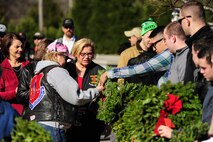 Volunteers from Seymour Johnson Air Force Base, North Carolina, and the local community hand out wreaths to event patrons during National Wreaths Across America Day at Evergreen Memorial Cemetery in Princeton, North Carolina, Dec. 13, 2014. During this second iteration of the event at Evergreen, approximately $4,500 was raised to fund the 450 wreaths that were laid during the ceremony. (U.S. Air Force photo by Airman 1st Class Brittain Crolley)