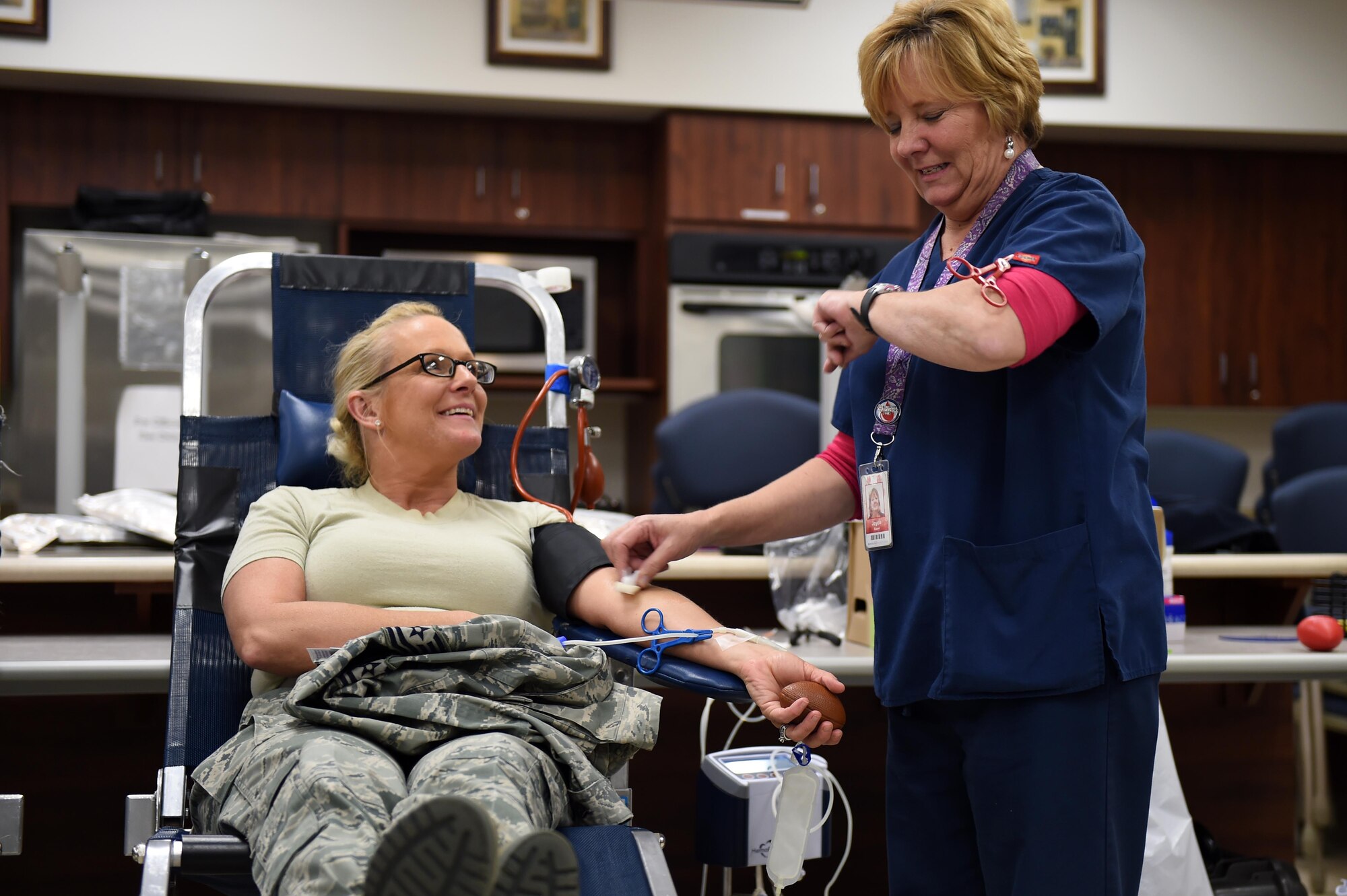 Tech. Sgt. Amanda Vonholtum, Air Reserve Personnel Center human resources, left, donates blood during the Bonfils Blood Center blood drive Dec. 17, 2014, at the Buckley Health Promotions Program. Many Team Buckley members attended the blood drive to raise awareness for the need of blood donors. (U.S. Air Force photo by Airman 1st Class Emily E. Amyotte/Released)