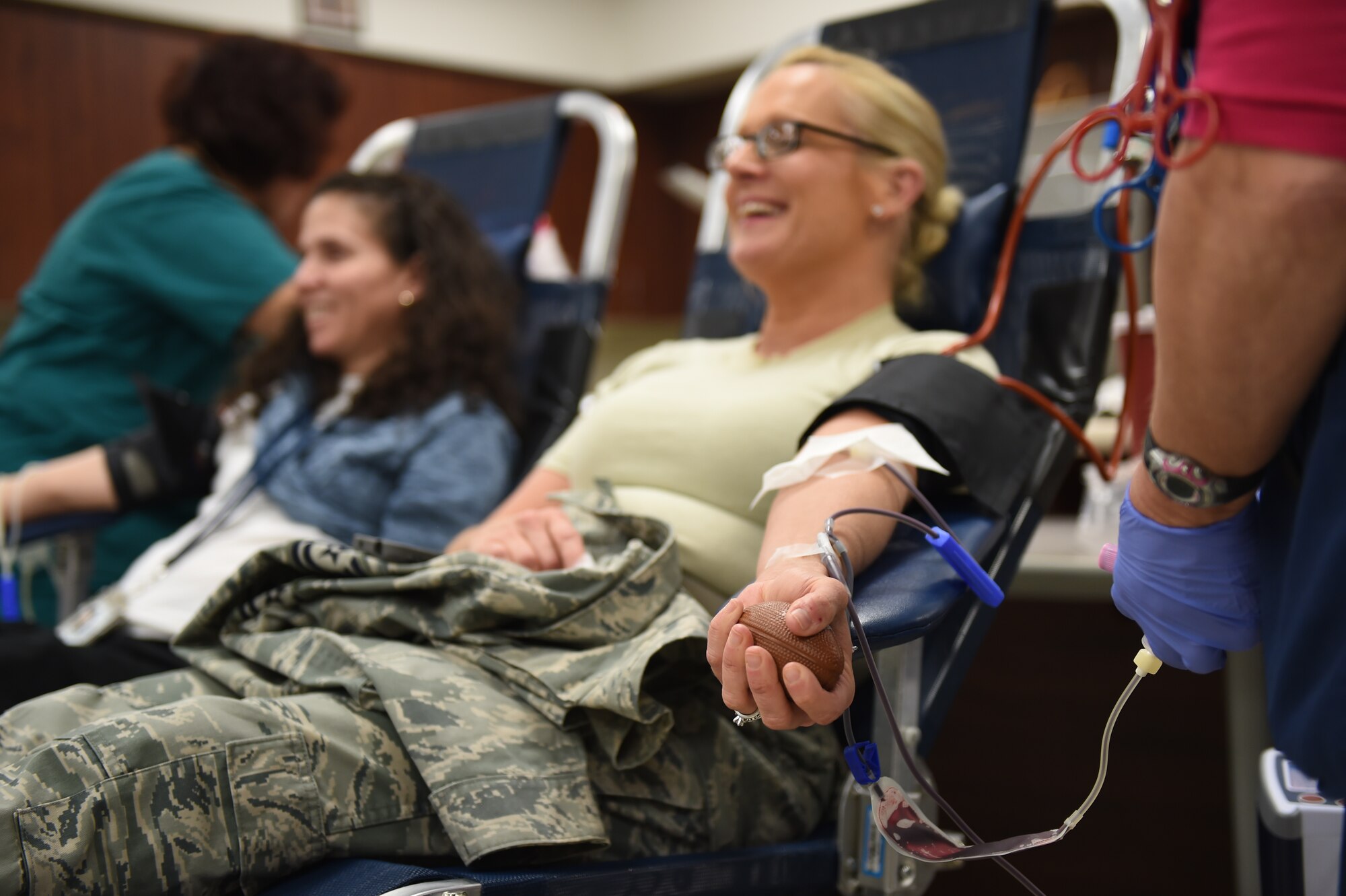 Tech. Sgt. Amanda Vonholtum, Air Reserve Personnel Center human resources, seated right, and Celiann Gonzalez, 460th Civil Engineer Squadron asset management chief, seated left, sit and chat while they donate blood during the Bonfils Blood Center blood drive Dec. 17, 2014, at the Buckley Health Promotions Program. Many Team Buckley members attended the blood drive to raise awareness for the need of blood donors. (U.S. Air Force photo by Airman 1st Class Emily E. Amyotte/Released)