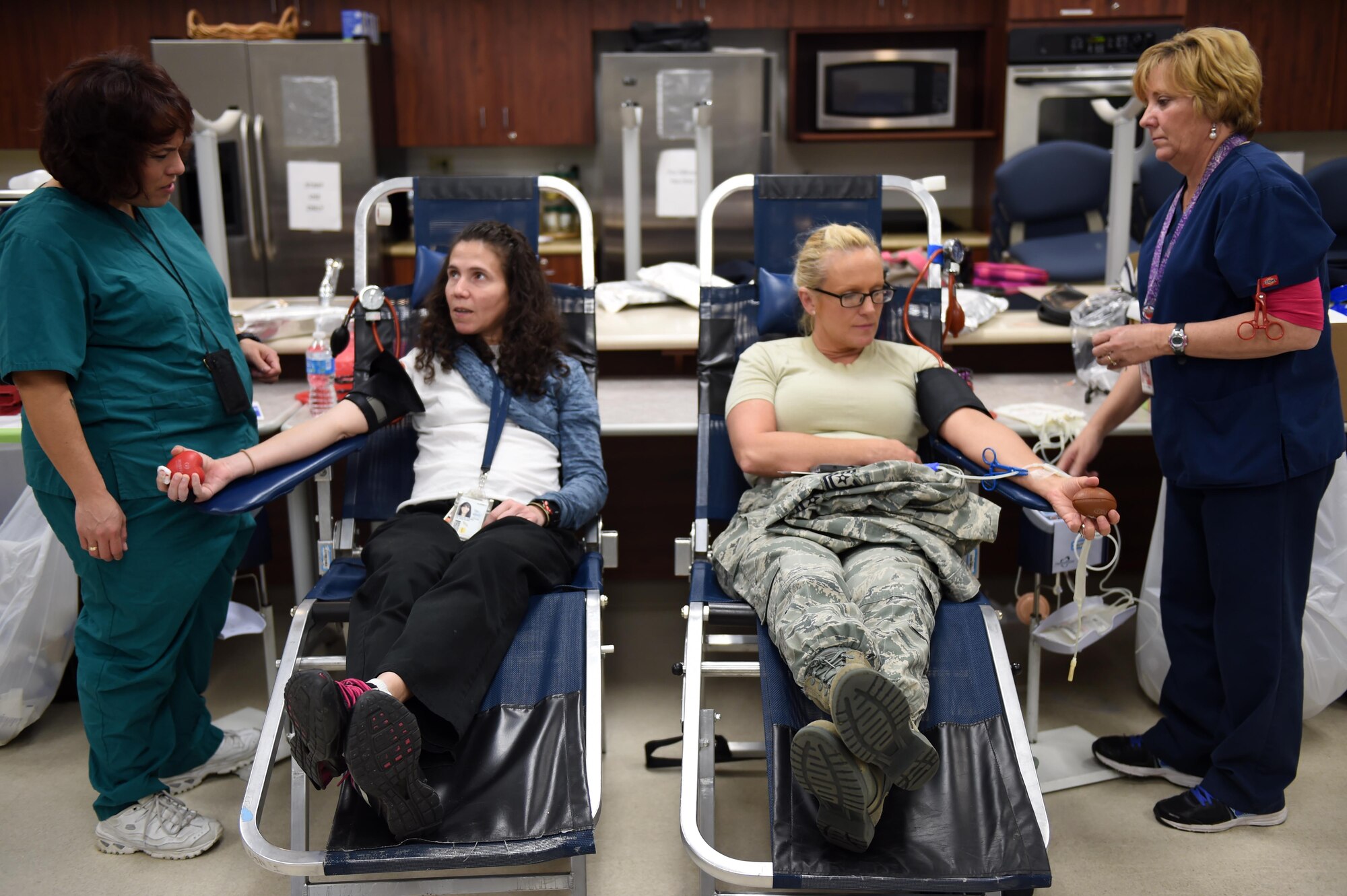 Tech. Sgt. Amanda Vonholtum, Air Reserve Personnel Center human resources, seated right, and Celiann Gonzalez, 460th Civil Engineer Squadron asset management chief, seated left, sit and chat while they donate blood during the Bonfils Blood Center blood drive Dec. 17, 2014, at the Buckley Health Promotions Program. Many Team Buckley members attended the blood drive to raise awareness for the need of blood donors. (U.S. Air Force photo by Airman 1st Class Emily E. Amyotte/Released)