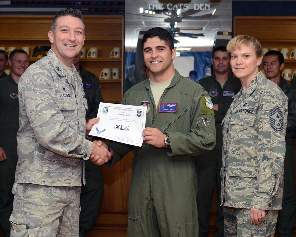 First Lt. Anthony Ruize, center, 434th Flying Training Squadron unit evaluation standardization monitor, poses with Col. Brian Hastings, left, 47th Flying Training Wing commander, and Chief Master Sgt. Teresa Clapper, right, 47th FTW command chief, after being presented the XLer of the week award here Dec. 17, 2014. The XLer is a weekly award chosen by wing leadership and is presented to those who consistently make outstanding contributions to their unit and Laughlin. (U.S. Air Force photo by Airman 1st Class Jimmie D. Pike)(Released)