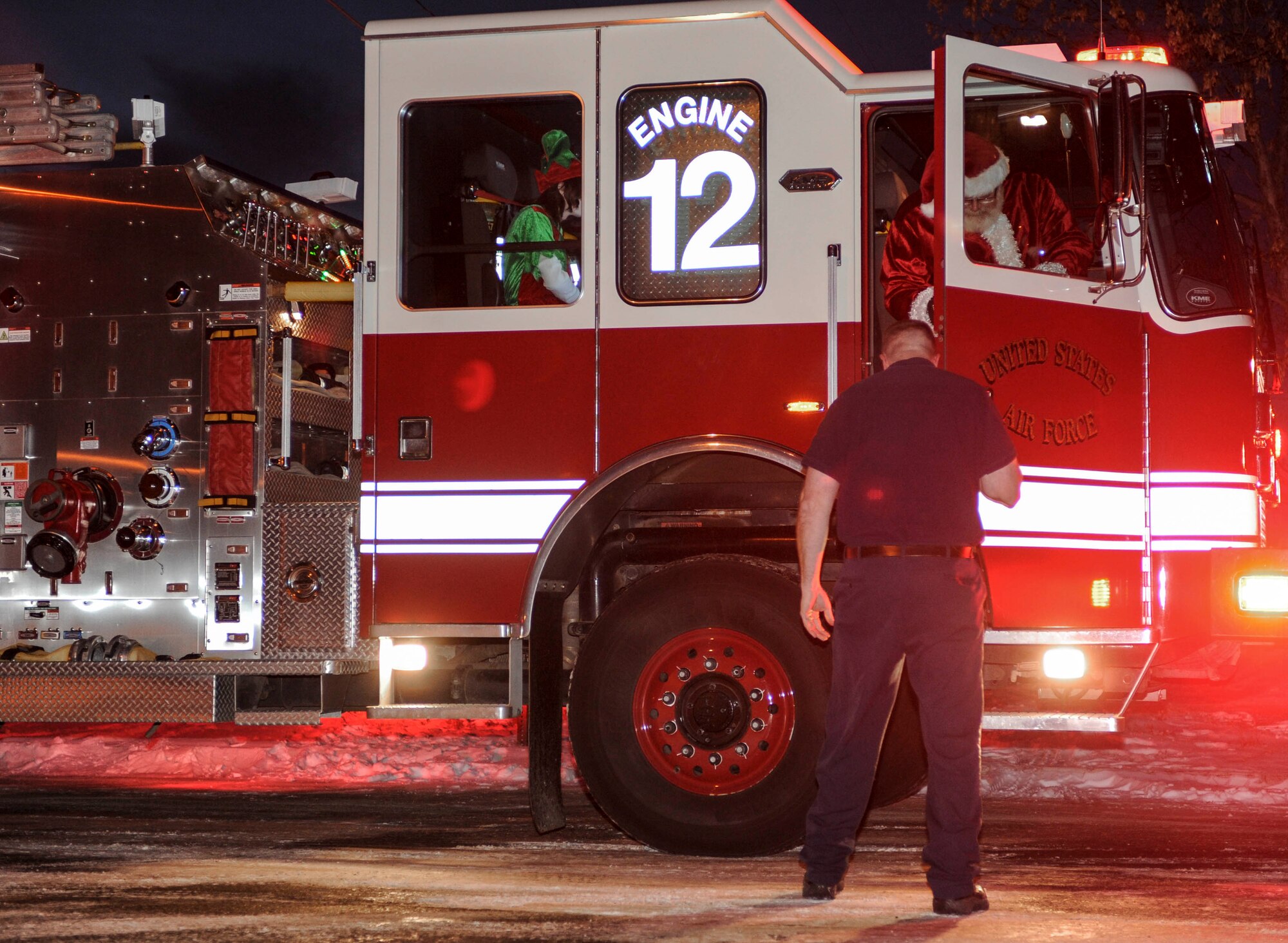 Santa Claus exits fire engine number 12 during the holiday tree lighting event hosted at the Jimmy Doolittle Center on Minot Air Force Base, N.D., Dec. 6, 2014. The event kicked off with a carol performed by local Boy Scouts and concluded with a social in the JDC. (U.S. Air Force photo/Senior Airman Stephanie Morris)