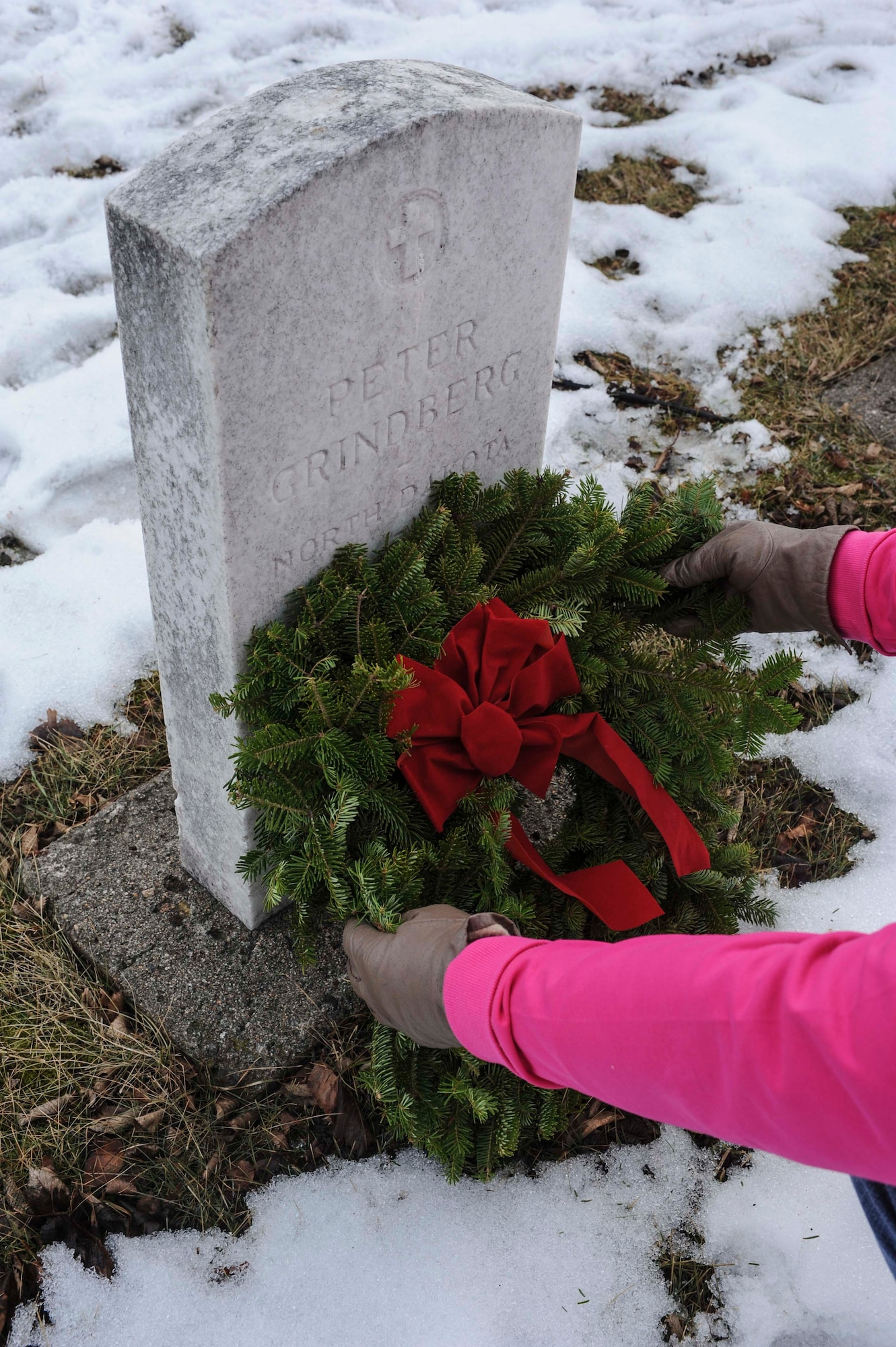 Minot native Lori Ammon places a wreath at the grave of Peter Grindberg during a ceremony commemorating national Wreaths Across America Day at Rosehill Memorial Park Cemetery in Minot, N.D., Dec. 13, 2014. Grindberg was a private first class who served in the 12 Field Hospital First Division, and he was one of many U.S. service members who had no recorded date of death on their headstone who may have been missing in action. (U.S. Air Force photo/Senior Airman Stephanie Morris)