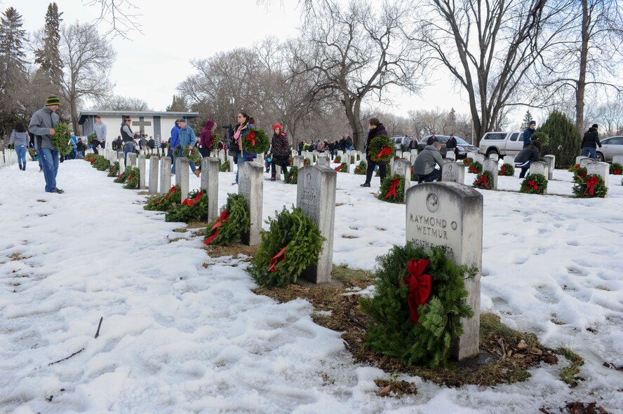 The headstones of veterans are lined through the snow as volunteers place wreaths on them during national Wreaths Across America Day, at Rosehill Memorial Park Cemetery in Minot, N.D., Dec. 13, 2014. Three hundred twelve wreaths were placed at Rosehill and Roosevelt Park  Cemetary, and an additional 57 “personal wreaths” were purchased and laid by individuals on graves of their loved ones.  (U.S. Air Force photo/Senior Airman Stephanie Morris)
