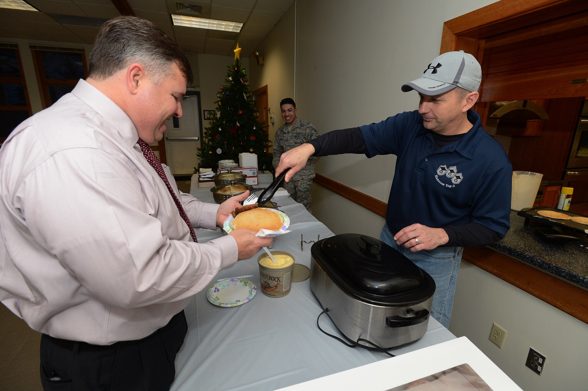 Hanscom Command Chief Master Sgt. Craig Poling, 66th Air Base Group, fills a plate for Tom Fredericks, Hanscom’s deputy director, at a pancake breakfast held at the Hanscom Air Force Base, Mass., chapel, Dec. 17, 2014.  The Chief's Group cooked and served a selection of sausage, juice, coffee and unlimited pancakes to Hanscom members during the breakfast. (U.S. Air Force photo by Jerry Saslav)