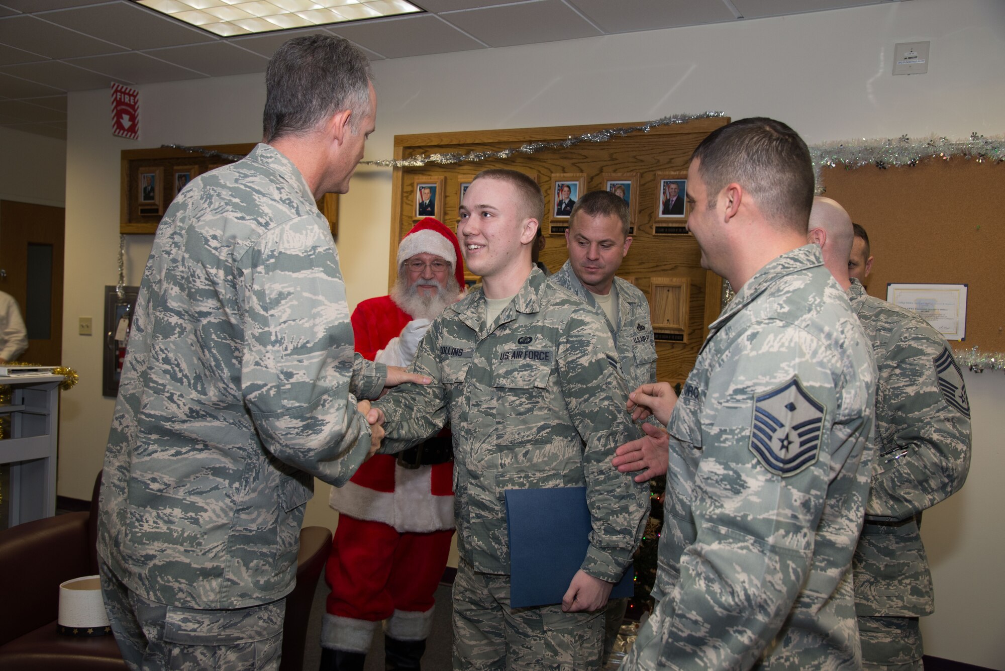 Col. Michael A. Vogel, 66th ABG commander, congratulates Airman 1st Class Mitchell Collins, Comptroller Squadron customer service technician, for earning a certificate of promotion to Senior Airman below the zone on Hanscom Air Force Base, Mass., Dec. 16, 2014.  BTZ is a competitive early promotion program offered to those in the rank of Airman first class who stand out from their peers and perform duties at a level above their current rank. (U.S. Air Force photo by Mark Herlihy)