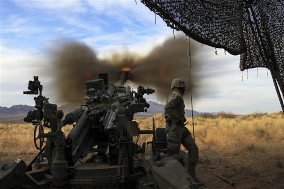 Army Spc. Macmillan Ekedede fires a round downrange during Exercise Iron Strike on Fort Bliss, Texas, Dec. 8, 2014. Ekedede, an assistant gunner, is assigned to Battery A, 2nd Battalion, 3rd Field Artillery Regiment, 1st Armored Division Artillery. 