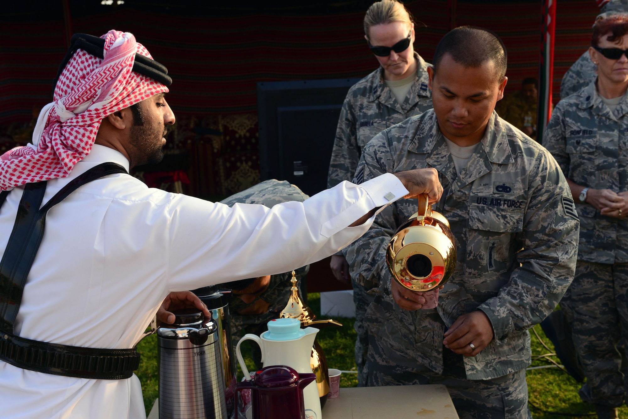 A U.S. Air Force Airman enjoys some Arabic tea at Al Udeid Air Base, Qatar.  The Qatari military invited U.S. servicemembers deployed to Al Udeid Air Base, Qatar, to celebrate Qatar National Day, over breakfast, on December 18, 2014. This year’s Qatar National Day celebration included a parade involving all branches of the Qatari military, police, and schools. The parade featured massive fire work displays, military aircraft flyovers, and many other demonstrations of national unity.  Qatar is a key and enduring regional partner of the United States.  (photo by Master Sgt. Kerry Jackson)                          