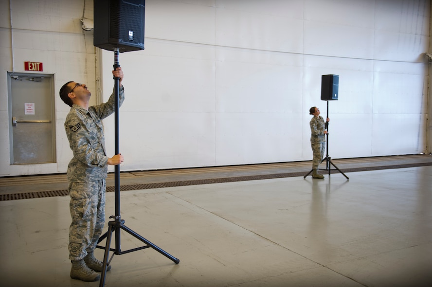 Staff Sgt. Erik Meza, 1st Special Operations Communications Squadron radio frequency transmision system technician supervisor, and Senior Airman Amanda Dalton, 1st Special Operations Communications Squadron radio frequency systems technician, setsup speakers for an awards ceremony at the Freedom Hangar on Hurlburt Field, Fla., Dec. 16, 2014. Some 1st SOCS Airmen are charged with an additional duty to setup audio systems for public address at base functions. (U.S. Air Force photo/Senior Airman Krystal M. Garrett)