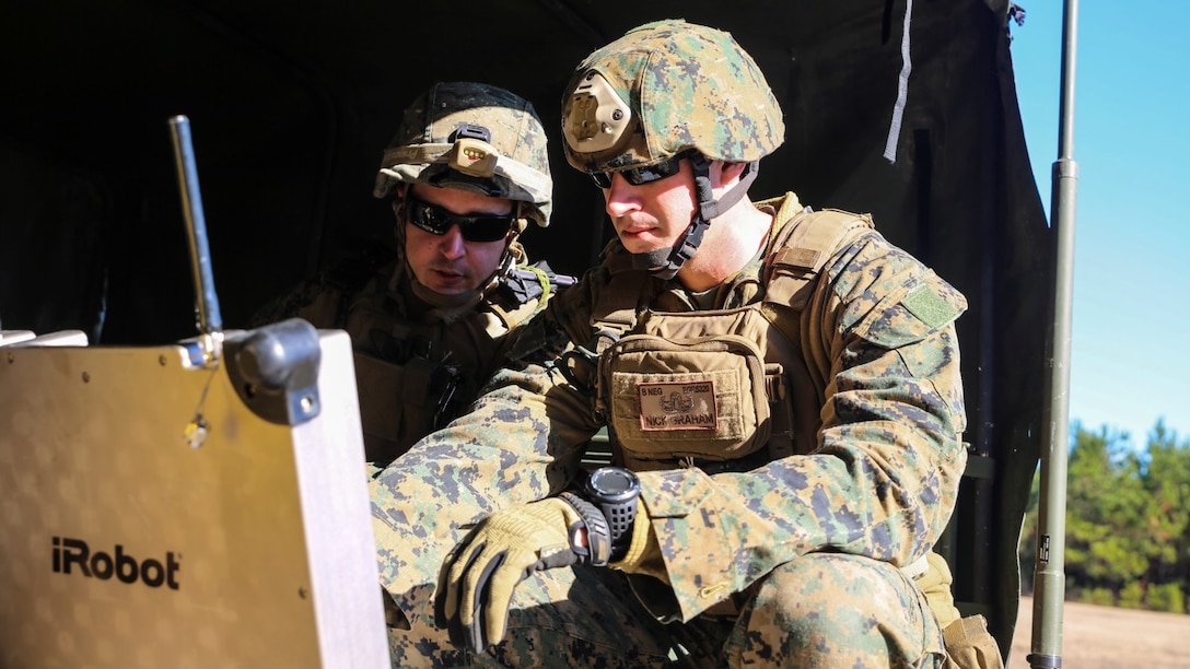 Sgt. James Downes, explosive ordnance disposal technician with Explosive Ordnance Disposal Company, 8th Engineer Support Battalion, and a Hermiston, Ore. native, and Sgt. Nick Graham, EOD technician with the unit and a Queen Creek, Ari. native, control a robot from their vehicle during a field training exercise Dec. 13, 2014, at EOD site 3 on Camp Lejeune, N.C. Robots allowed EOD techs to view and assess their surroundings from a distance during simulated possible improved explosive device threats. 