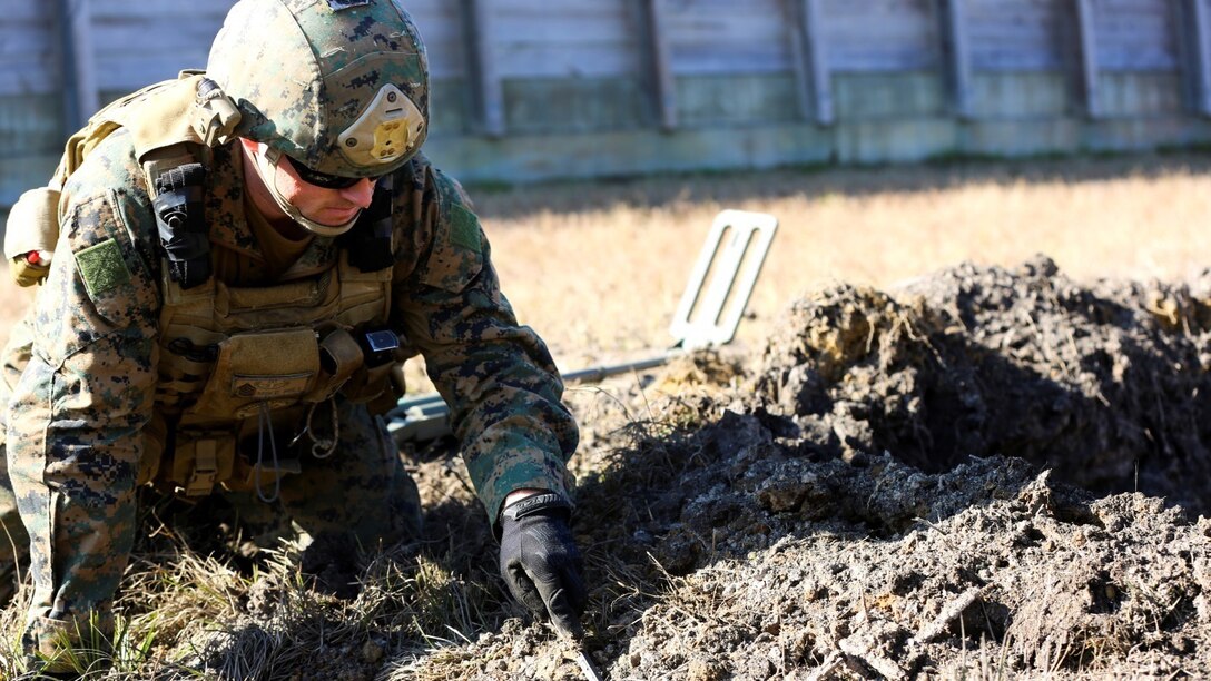 Staff Sgt. Mike Hill, explosive ordnance disposal technician with Explosive Ordnance Disposal Company, 8th Engineer Support Battalion, probes the dirt at a blast site during a simulated post-blast analysis call during a field exercise at EOD site 3 at Camp Lejeune, N.C., Dec. 15, 2014.  EOD techs used probes to search for any buried improvised explosive devises.