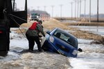 Sgt. Preston Steele and Spc. Jeremy Kasperson, both of the 815th Engineer
Company, attach a towing chain to a partially submerged vehicle March 25 on a washed out portion of a gravel road a few miles west of Harwood, N.D. Steele and Kasperson are members of a North Dakota National Guard quick response force team that is being called to the scene by the Cass County Sheriff's Department to assist with the vehicle recovery. The driver of the vehicle was able to get clear of the car and make his way through the freezing water to safety before help arrived.