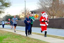 Santa Claus leads a couple of Air Commandos to the finish line during the Jingle Bell 5K Fun Run on Hurlburt Field, Fla., Dec. 19, 2014. Many race participants dressed up for the 5K in spirit of the upcoming holidays. (U.S. Air Force photo/Airman 1st Class Andrea Posey)