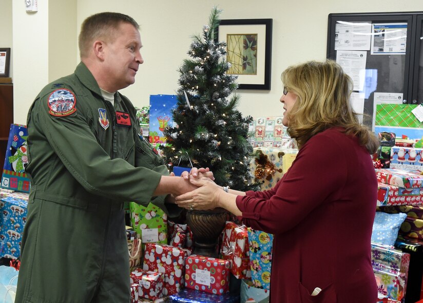 Col. James Cluff, 432nd Wing/432nd Air Expeditionary Wing commander, greets Kimberly Guerino, Indian Springs school registrar, during the 2014 Holiday Gift Drive open house event at the Airmen Ministry Center at Creech Air Force Base, Nevada, Dec. 16, 2014. The Creech Chapel first began the gift drive in 2010, and this year’s donations supported 110 children who attend Indian Springs elementary, middle and high schools. (U.S. Air Force Photo by Tech. Sgt. Shad Eidson/released)