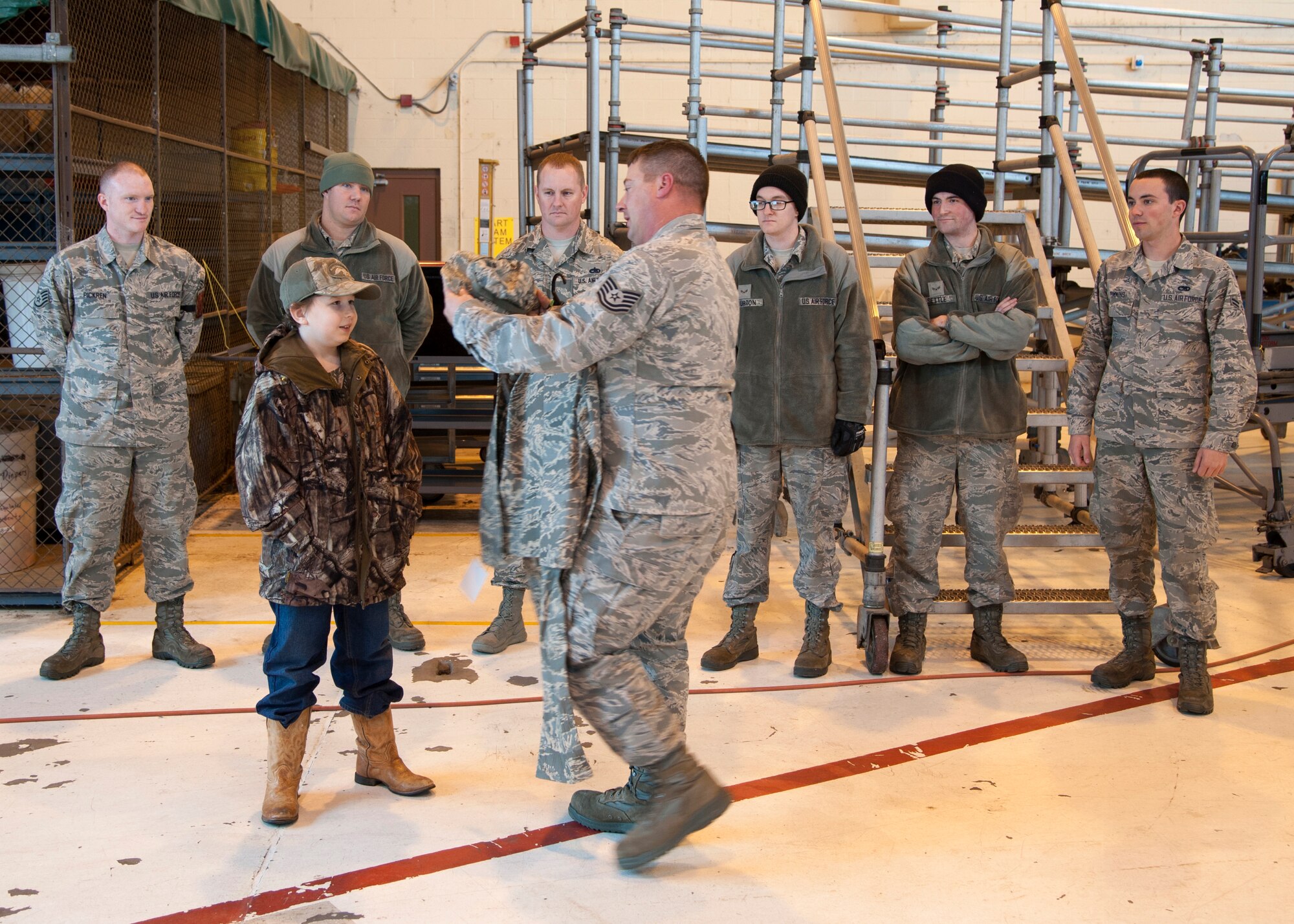 Maxwell Matlock, 10, receives an Airman Battle Uniform from Tech. Sgt. Mark Haines, 2nd Maintenance Group maintenance operation squadron NCO in-charge, on Barksdale Air Force Base, La., Dec. 18, 2014. Matlock, a child diagnosed with high-risk T Cell Acute Lymphoblastic Leukemia, was given a tour of a B-52H Stratofortress, presented with several items and received the title of Honorary Crew Chief. (U.S. Air Force photo/Senior Airman Joseph A. Pagán Jr.)