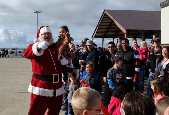 Santa Claus greets children during the Children's Holiday Party at Beale Air Force Base, Calif., Dec. 13, 2014. Santa posed for photos and helped with the distribution of thousands wrapped presents. (U.S. Air Force photo by Staff Sgt. Robert M. Trujillo/Released)