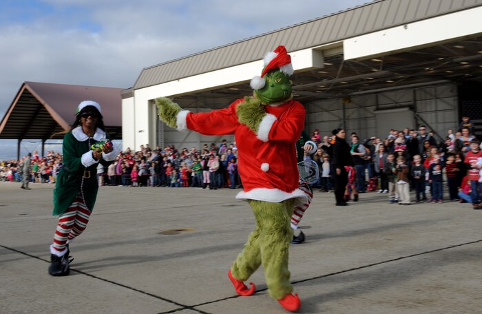 The Grinch runs away from Santa's elves during the Children's Holiday Party at Beale Air Force Base, Calif., Dec. 13, 2014. After chasing off the Grinch, the elves posed for photos and helped with the distribution of thousands wrapped presents. (U.S. Air Force photo by Staff Sgt. Robert M. Trujillo/Released)