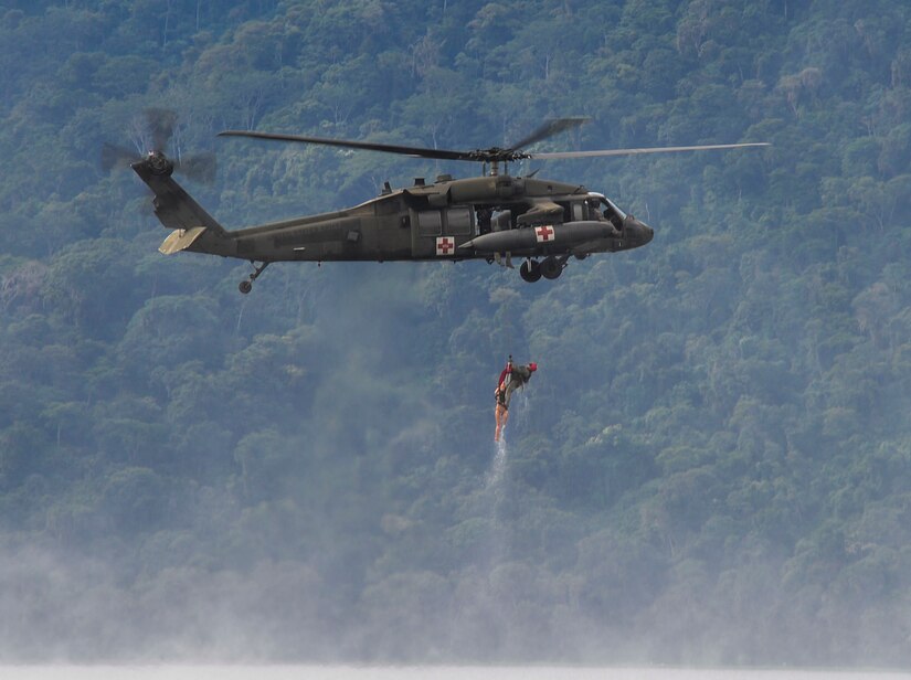 A medic from the 1-228th Aviation Battalion holds on to a rescue mannequin as they are being hoisted into a UH-60 Black Hawk helicopter over Lake Yojoa, Honduras, Dec. 18, 2014.   The 1-228th AVN BN spent the afternoon practicing overwater hoist training.  The overwater hoist training was held to ensure members of Joint Task Force-Bravo are planning and preparing for crisis and contingency response as part of U.S. Southern Command’s mission. Contingency planning prepares the command for various scenarios that pose the greatest probability of challenging our regional partners or threatening our national interests.  (U.S. Air Force photo/Tech. Sgt. Heather Redman)