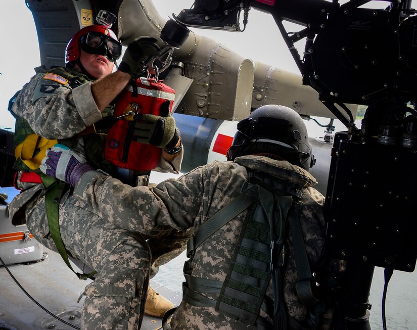 A medic from the 1-228th Aviation Battalion prepares to be lowered from a UH-60 Black Hawk helicopter to retrieve a rescue mannequin in Lake Yojoa, Honduras, Dec. 18, 2014.   The 1-228th AVN BN spent the afternoon practicing overwater hoist training.  The overwater hoist training was held to ensure members of Joint Task Force-Bravo are planning and preparing for crisis and contingency response as part of U.S. Southern Command’s mission. Contingency planning prepares the command for various scenarios that pose the greatest probability of challenging our regional partners or threatening our national interests.  (U.S. Air Force photo/Tech. Sgt. Heather Redman)