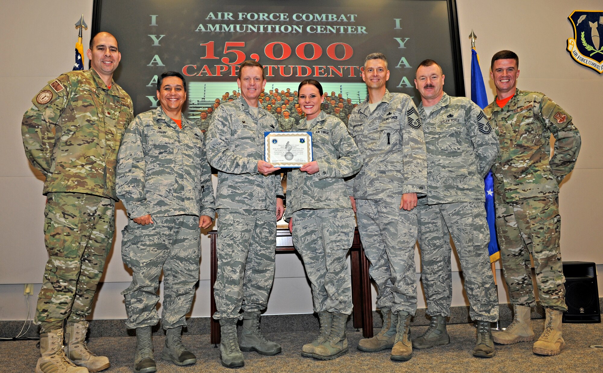 Staff Sgt. Olivia Tipton (center), Air Force Combat Ammunition Center student from the 509th Munitions Squadron, Whiteman Air Force Base, Mo., receives a certificate of completion from Col. Douglas J. Lee, 9th Reconnaissance Wing commander, and AFCOMAC leadership after completing the munitions upgrade training course as the 15,000 student at Beale Air Force Base, Calif., Dec. 19, 2014. AFCOMAC has provided the Air Force munitions community with advanced training in mass combat ammunition planning and production techniques since 1984. (U.S. Air Force photo by Airman 1st Class Ramon A. Adelan/Released)