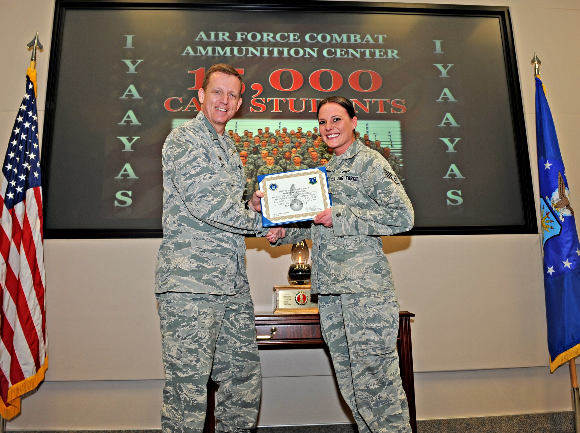 Staff Sgt. Olivia Tipton (right), Air Force Combat Ammunition Center student from the 509th Munitions Squadron, Whiteman Air Force Base, Mo., receives a certificate of completion from Col. Douglas J. Lee, 9th Reconnaissance Wing commander, after completing the munitions upgrade training course as the 15,000 student at Beale Air Force Base, Calif., Dec. 19, 2014. AFCOMAC has provided the Air Force munitions community with advanced training in mass combat ammunition planning and production techniques since 1984. (U.S. Air Force photo by Airman 1st Class Ramon A. Adelan/Released)