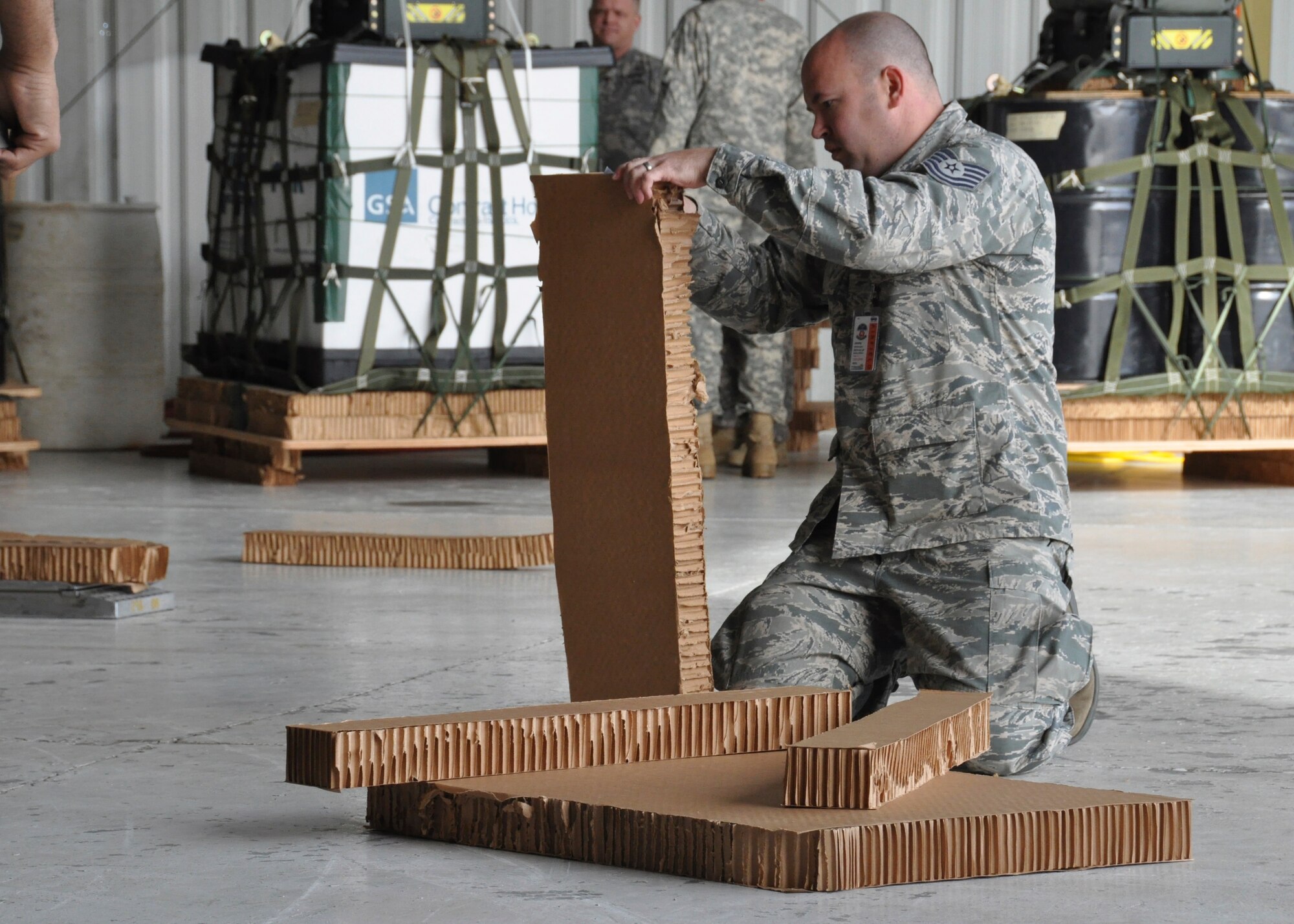 Tech. Sgt. Jeremy Wetherington, member of the 80th Aerial Port Squadron, cuts strips of honeycomb cardboard to place under pallets at Yuma, Arizona, Dec. 15, 2014. The pallets were to be airdropped from C-130's during Desert University Training. (U.S. Air Force Photo by Senior Airman Miles Wilson)