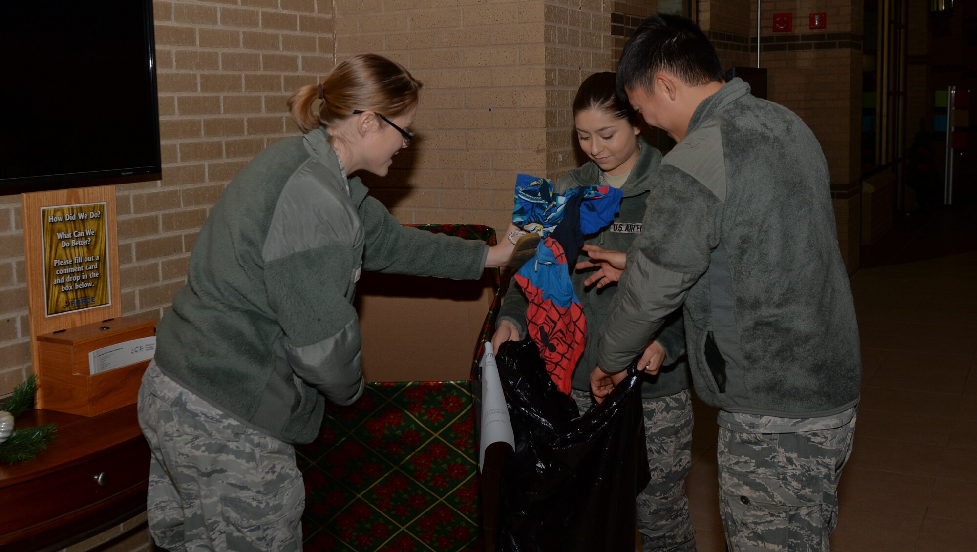 Airmen 1st Class Rebecca Rios, Thanh Chu and Senior Airman Heather Bell, collect clothing from the donation box in the Robert J. Dole Center Dec. 10, 2014, at McConnell Air Force Base, Kan. The three 22nd Communication Squadron Airmen, put together a clothing drive to help clothe people in need. (U.S. Air Force photo/Senior Airman Colby L. Hardin)