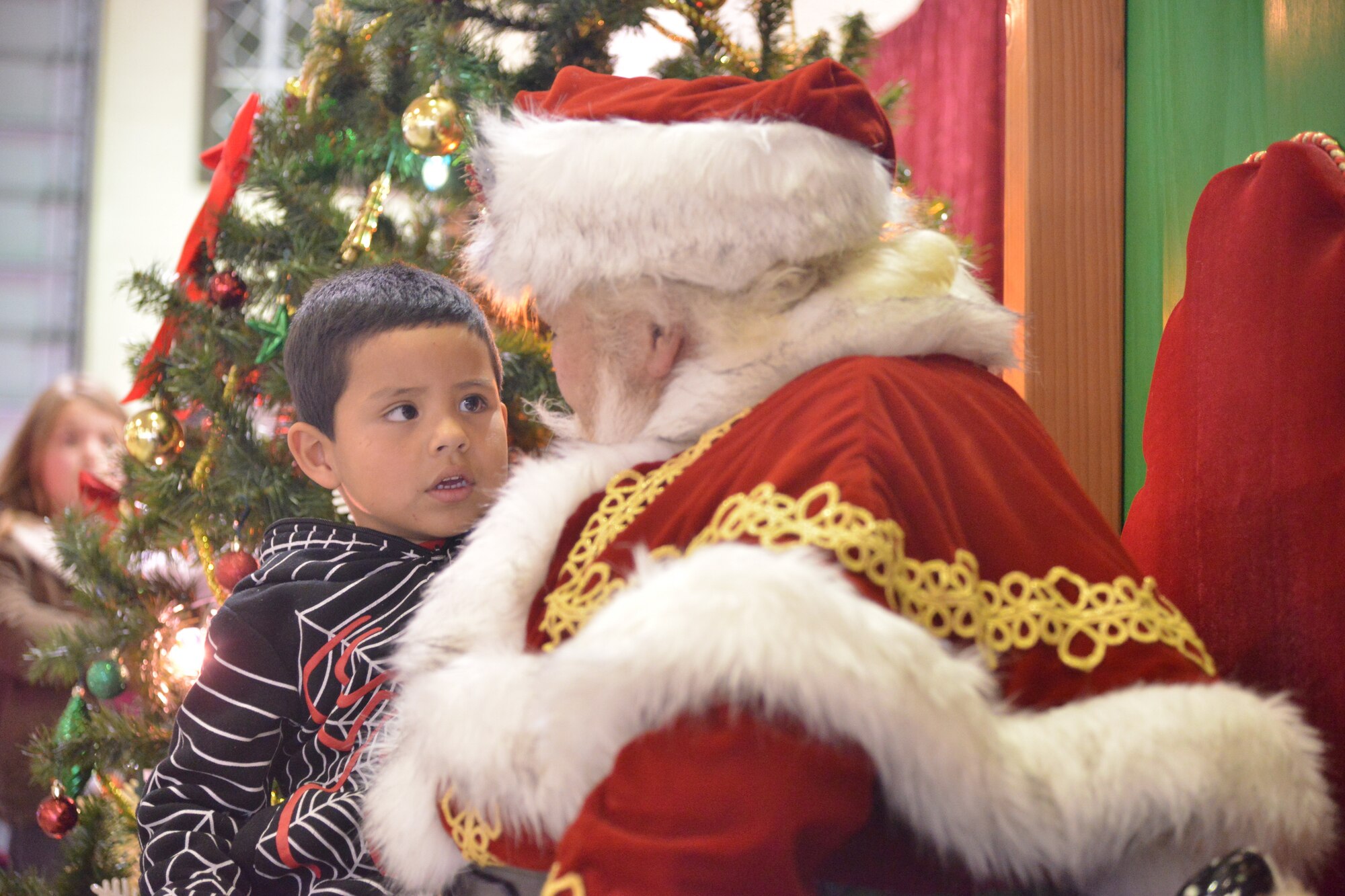 Angel Ibarra talks to Santa at the Operation Holiday Cheer event Dec. 17. Lunch was served to about 2,000 people from local communities, and more than 800 toys were given away to children. Operation Holiday Cheer is sponsored by the Kirtland Fire Department and is one of the base's biggest charity events of the year. (Photo by Todd Berenger)