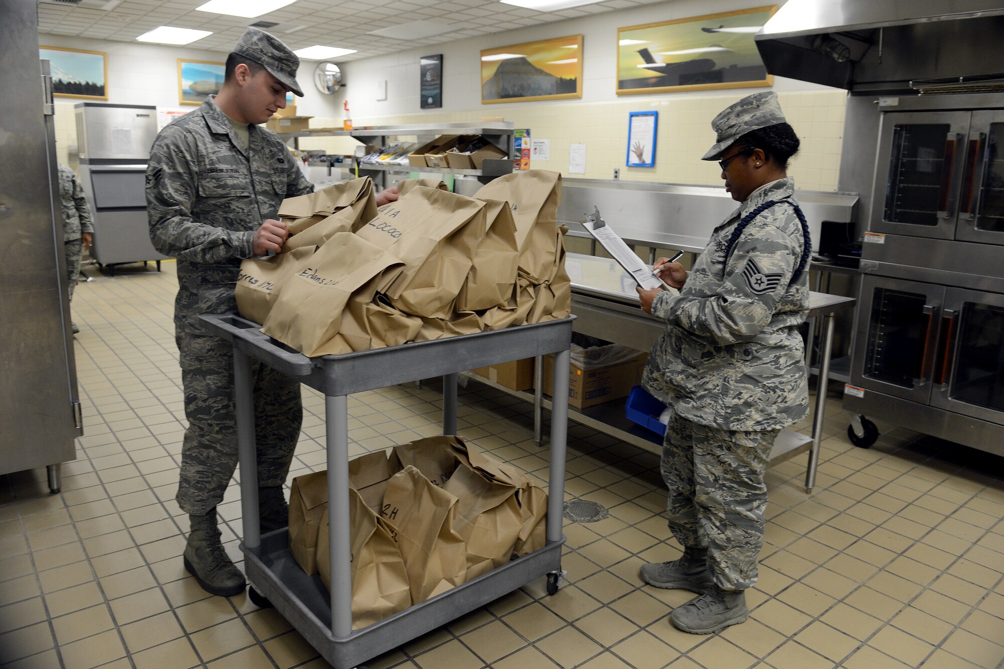 Staff Sgt. Marqueta Westmoreland (right), 373rd Training Squadron military training leader, confirms her order with Airman 1st Class Jose Lara Balderrama, 627th Force Support Squadron food services journeyman Dec. 18, 2014, at Joint Base Lewis-McChord, Wash. There is a variety of flight kitchen meals, with more than 220 different meal combinations, and 12 different types of Meals, Ready to Eat. (U.S. Air Force photo/Airman 1st Class Keoni Chavarria)