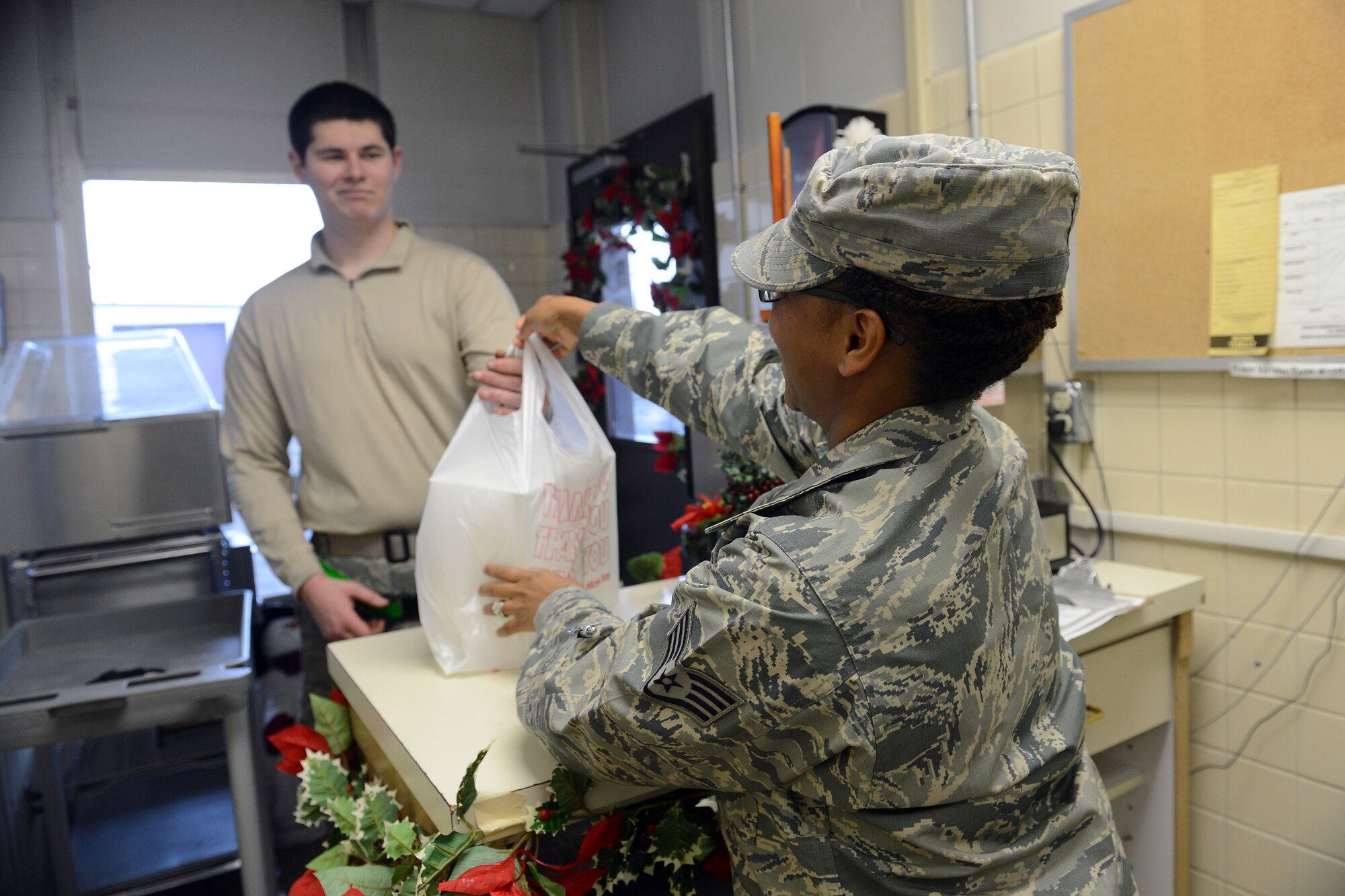 Staff Sgt. Monica Snow (right), 627th Force Support Squadron NCO in charge of the flight kitchen, gives a ground meal to Airman 1st Class Charles Roscoe, 62nd Aircraft Maintenance Squadron crew chief Dec. 18, 2014, at Joint Base Lewis-McChord, Wash. The flight kitchen is a 24-hour shop, creating more than 2,200 meals a month depending on mission requirements. (U.S. Air Force photo/Airman 1st Class Keoni Chavarria)