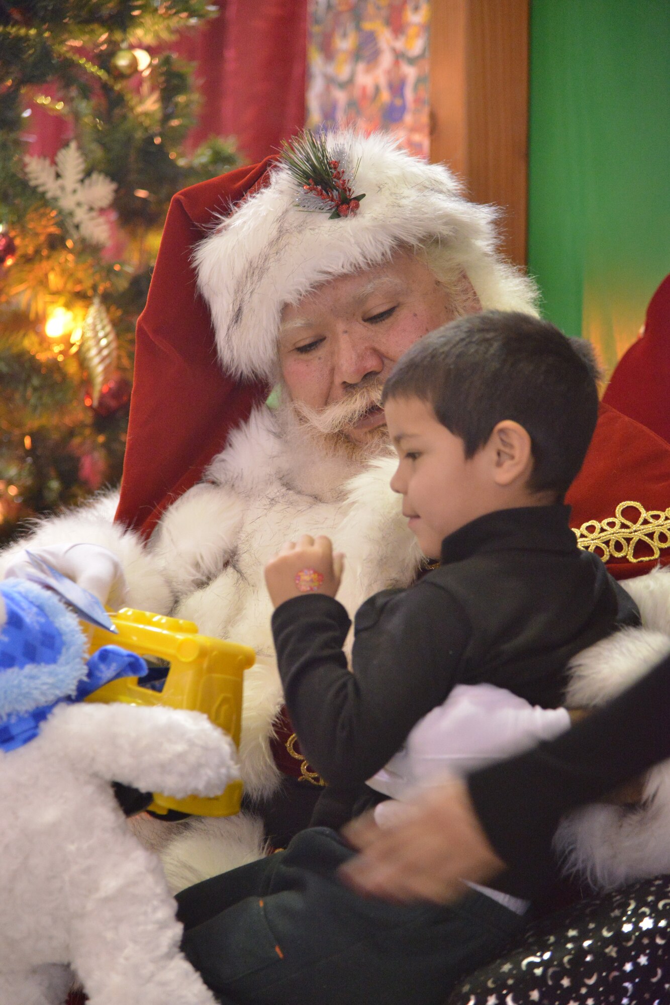 Jose Martinez receives a toy from Santa at the Operation Holiday Cheer event. More than 800 toys were given to kids from the local communities during the event.  It's sponsored by the Kirtland Fire Department and is one of the base's biggest charity events of the year. (Photo by Todd Berenger)