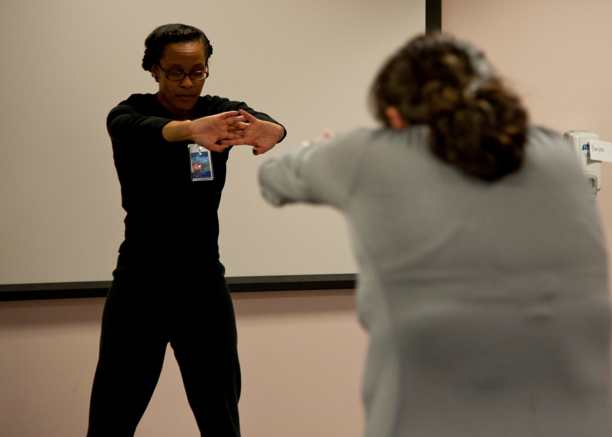 PETERSON AIR FORCE BASE, Colo. – Dana Johnson, Health and Wellness Center health educator, instructs a short work out for the participants attending the 12-week weight management program, Dec. 15, 2014. During the program, which is geared towards adults, participants learn ways to ease into a healthy lifestyle, lose body fat and maintain everything for a long period of time. (U.S. Air Force photo by Senior Airman Tiffany DeNault)