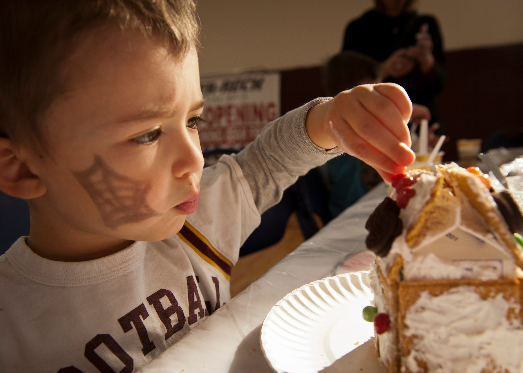 PETERSON AIR FORCE BASE, Colo. – Brayden Hendrickson, 3, carefully sets a red candy on top of his gingerbread house to complete the look at the Winter Wonderland event held at the R. P. Lee Youth Center, Dec. 13, 2014. The second annual Winter Wonderland was held to celebrate the beginning of the winter season and the holidays with crafts, face painting, snacks, Santa and much more. (U.S. Air Force photo by Airman 1st Class Rose Gudex)