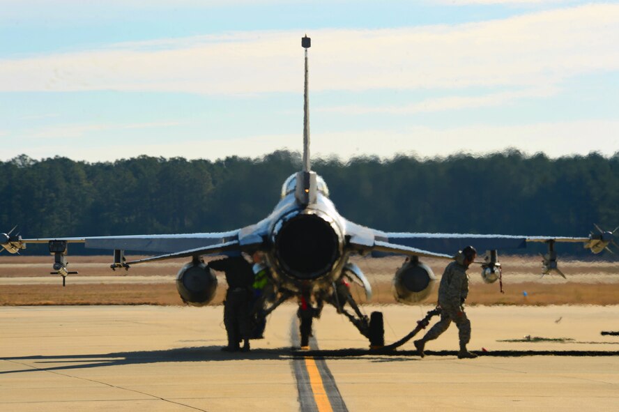 A U.S. Air Force Airman assigned to the 20th Logistic Readiness Squadron fuels management flight, drags a fuel hose after a hot pit refueling at Shaw Air Force Base, S.C., Dec. 18, 2014. Typically done in combat situations, hot pits are performed to quickly refuel the aircraft while the engine is running. (U.S. Air Force photo by Senior Airman Jensen Stidham/Released)
