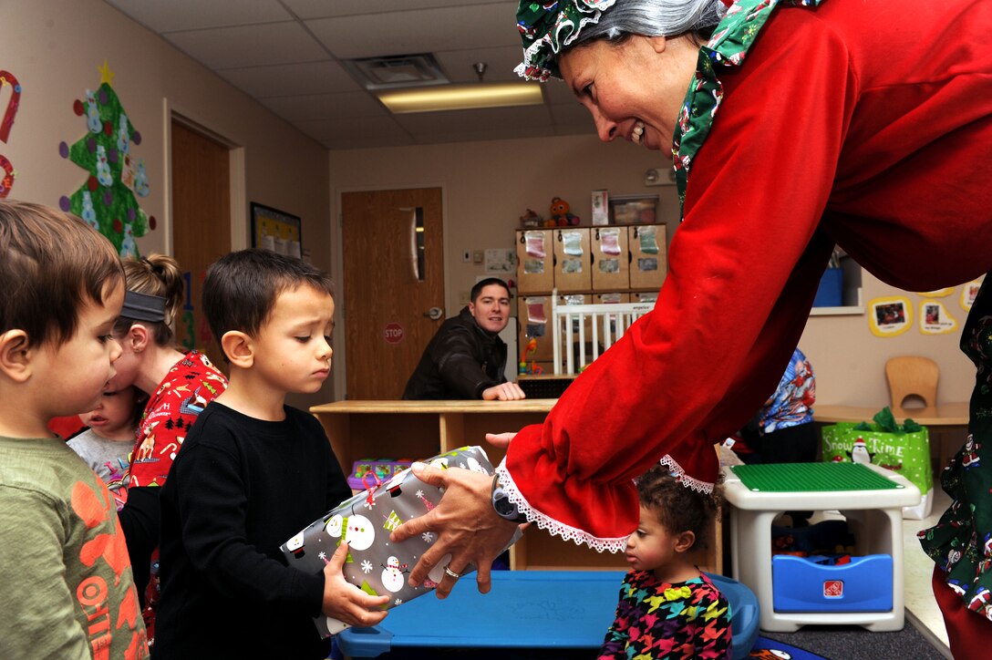 Mrs. Claus hands out gifts to children enrolled in Youth and Family Services Child Development Center programs in Rapid City, S.D., Dec. 16, 2014. More than 160 gifts were given to children enrolled at the YFS CDC by Santa, Mrs. Claus and more than 30 volunteers. (U.S. Air Force photo by Senior Airman Hailey R. Staker/Released)