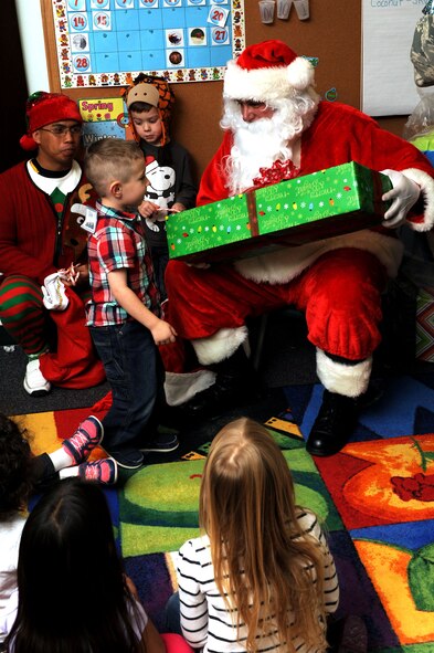 Santa hands a gift to a child at the Youth & Family Services Child Development Center in Rapid City, S.D., Dec. 16, 2014. (U.S. Air Force photo by Senior Airman Hailey R. Staker/Released)