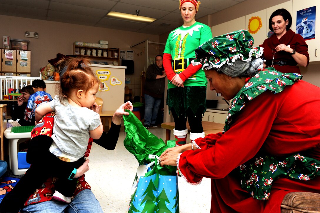 A child opens a gift from Mrs. Claus at the Youth & Family Services Child Development Center in Rapid City, S.D., Dec. 16, 2014. (U.S. Air Force photo by Senior Airman Hailey R. Staker/Released)