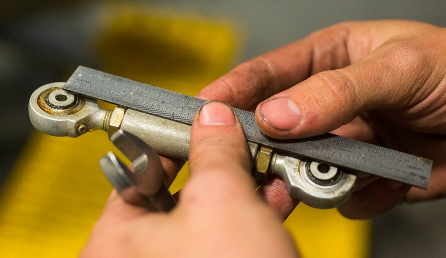 U.S. Air Force Staff Sgt. Richard Adcock, 23d Equipment Maintenance Squadron aerospace propulsion craftsman, measures a control rod during an isochronal inspection Dec. 8, 2014, at Moody Air Force Base, Ga. Adcock measured the length of the rod and made adjustments until it was the necessary length to function properly. (U.S. Air Force photo by Airman 1st Class Ceaira Tinsley/Released)