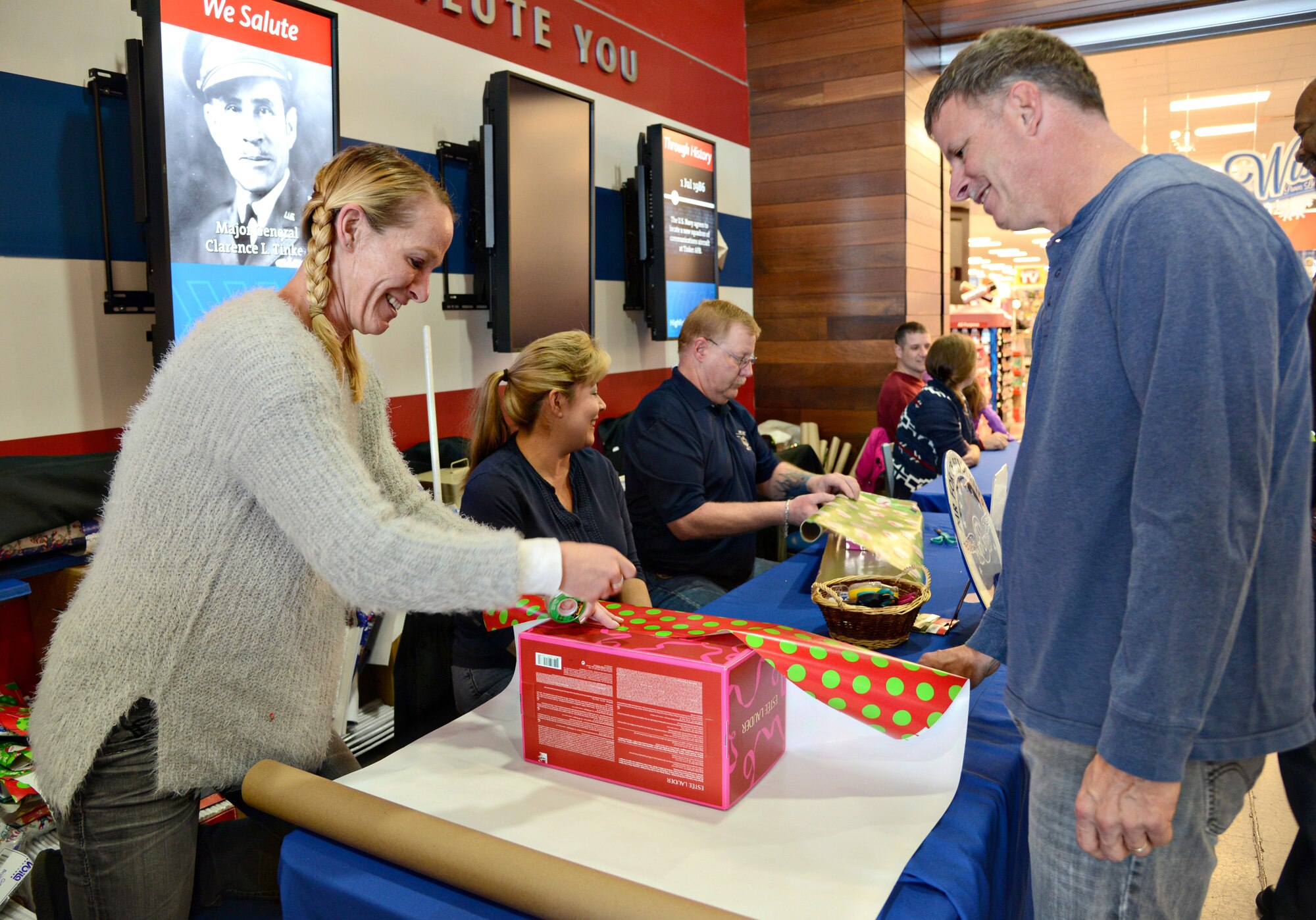 Air Force Sustainment Center Command Chief Master Sgt. Gregg Jones and spouse, Sarah, wrap shoppers’ Christmas gifts at the Tinker Exchange on Dec. 10 in support of the Air Force Sergeant’s Association. (Air Force photo by Kelly White)