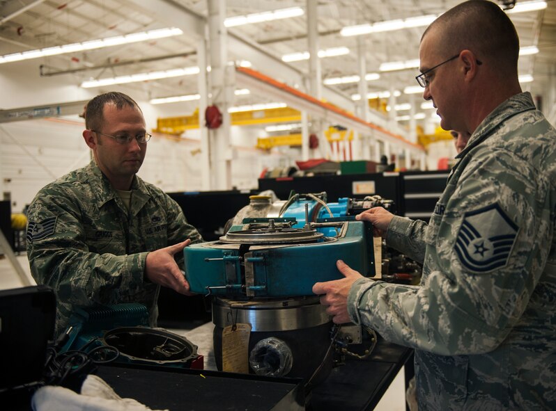 U.S. Air Force Master Sgt. Eric Horton, right, and Tech. Sgt. Michael Griggs, 23d Component Maintenance Squadron aerospace propulsion craftsmen, attach a gear box to a GTCP-3650 auxiliary power unit (APU) Dec. 15, 2014, at Moody Air Force Base, Ga. The APU is a small gas turbine engine that provides power to the TF-34 engine on the A-10C Thunderbolt II. (U.S. Air Force photo by Senior Airman Olivia Bumpers/Released)