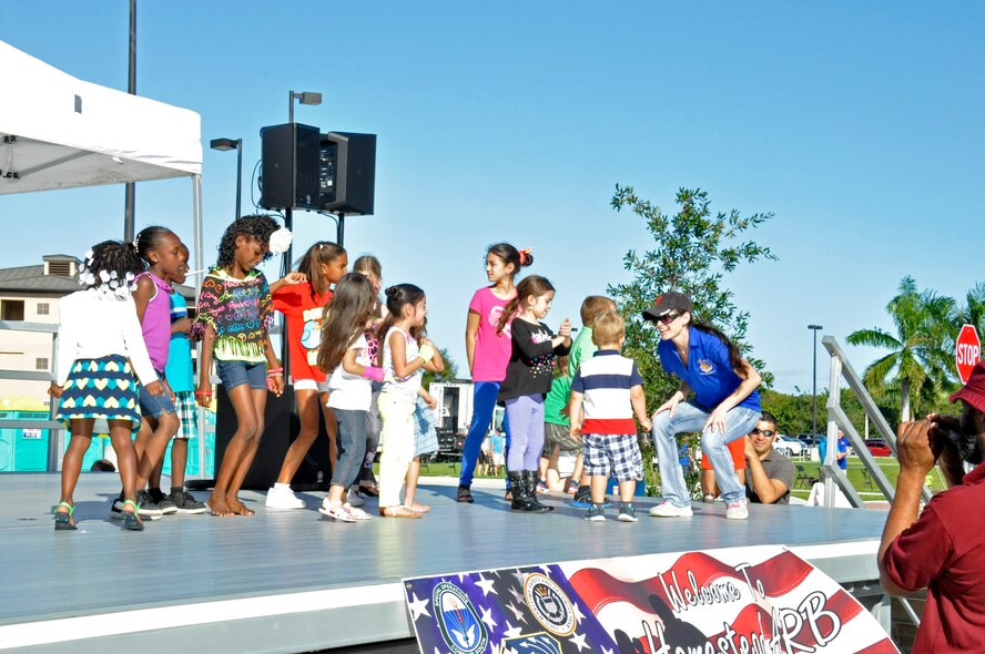 Staff Sgt. Veronica Simpson, 482nd Fighter Wing chaplain’s assistant, leads a group of children in a dance on-stage during the Family Day at Homestead Air Reserve Base, Fla., Dec. 6. The Family Day was a free event that leadership held as a way of thanking all the Airmen and their families for their dedication and sacrifice throughout the year. (U.S. Air Force photo by Nicholas Caceres)