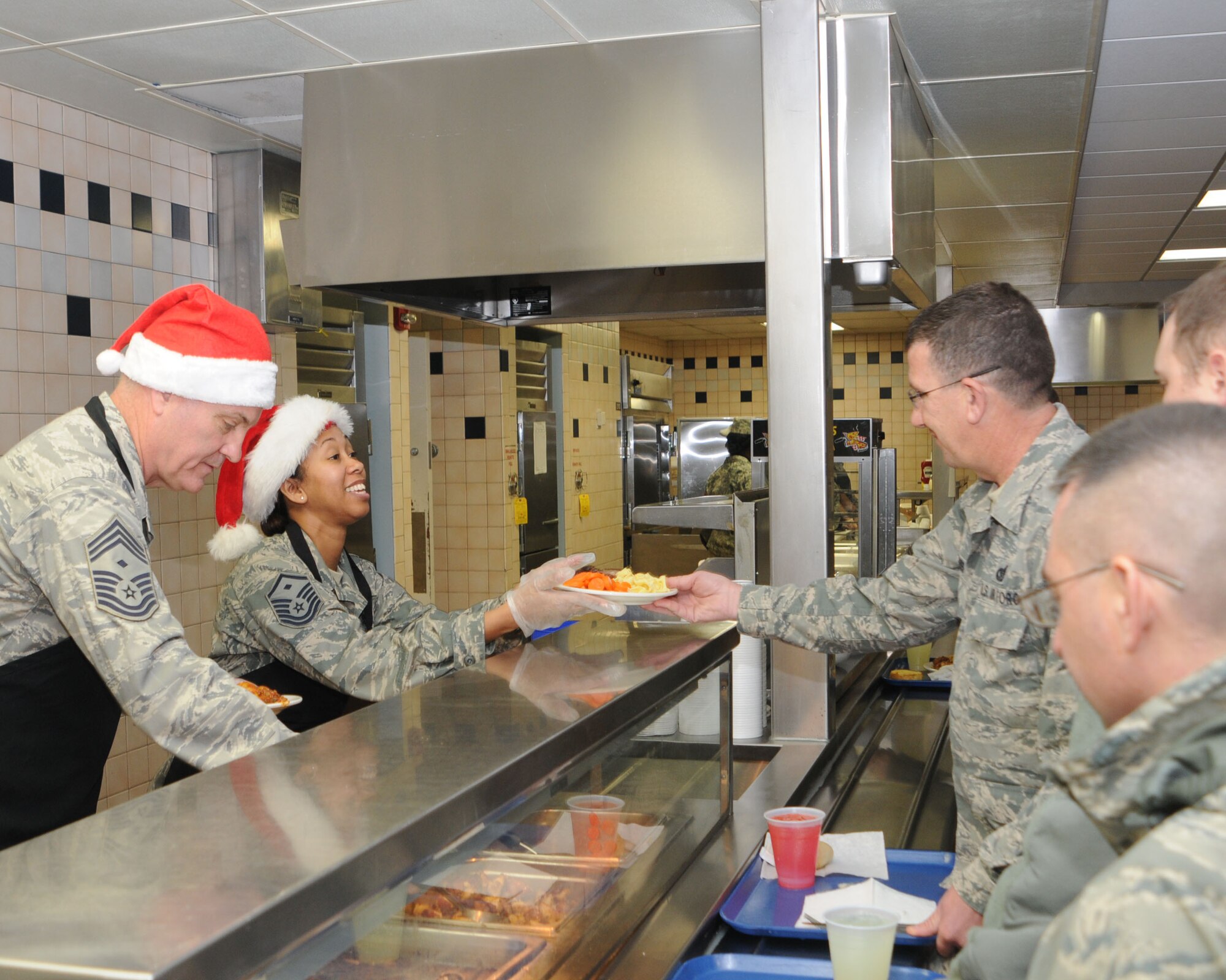 YOUNGSTOWN AIR RESERVE STATION, Ohio -- Air Force Reserve Chief Master Sgt. Douglas Shepard, first sergeant of the 910th Maintenance Squadron, and Master Sgt. Virginia Wynn, first sergeant of the 910th Maintenance Group, serve the holiday meal at the Community Activity Center here, Dec. 7, 2014. Unit first sergeants serving the holiday meal to the wing’s Citizen Airmen is a long standing 910th Airlift Wing tradition. U.S. Air Force photo/Tech. Sgt. Rick Lisum 
