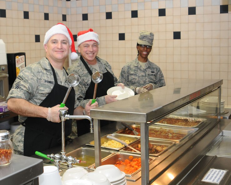 YOUNGSTOWN AIR RESERVE STATION, Ohio -- Air Force Reserve Master Sgt. John Pounds, first sergeant of the 910th Aircraft Maintenance Squadron and Master Sgt. James Masotto, first sergeant of 76th Aerial Port Squadron, along with Senior Airman Franchisca Thompson, a services technician assigned to the 910th Force Support Squadron, prepare to serve the holiday meal at the Community Activity Center here, Dec. 7, 2014. Unit first sergeants serving the holiday meal to the wing’s Citizen Airmen is a long standing 910th Airlift Wing tradition.  U.S. Air Force photo/Tech. Sgt. Rick Lisum 