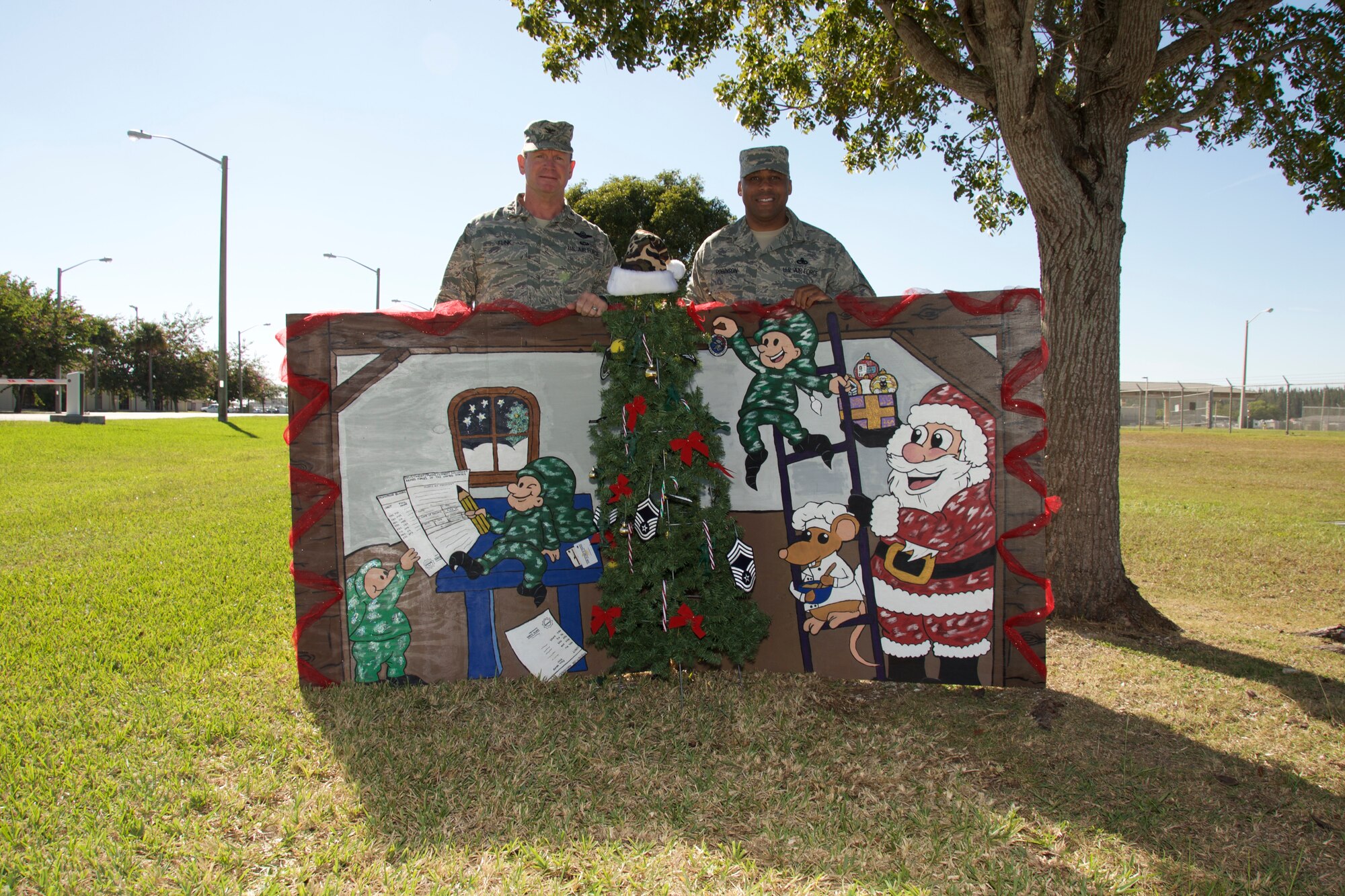 Col. Chris Funk, 482nd Fighter Wing commander, and Command Chief Master Sgt. Katdo Robinson, 482nd FW command chief, pose with the winning holiday card on Dec. 11, at Homestead Air Reserve Base, Fla. Robinson said this card won by a vote in the command suite, and was chosen because of all the intricate details and hard work put into the making of this card. The winning card was hand-drawn and painted by the 482nd Force Support Squadron.