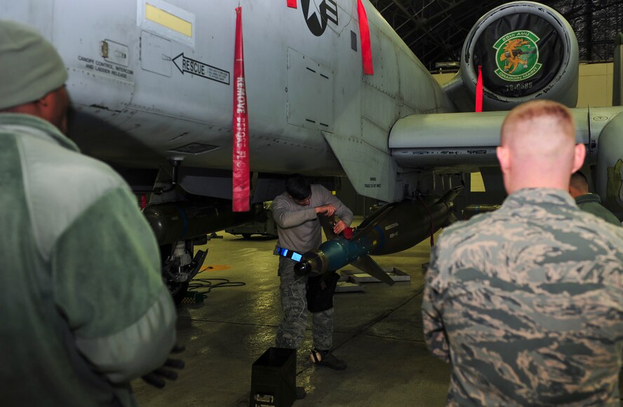 Weapons standardization members watch Senior Airman Anthony Cicchino, 51st Maintenance Operations Flight load crew member, tighten a bolt on the computer control group on a bomb during a weapons standardization inspection Dec. 16, 2014, at Osan Air Base, Republic of Korea. The load crew members are required to be recertified on the 15 different munitions every 30-days. (U.S. Air Force photo by Senior Airman David Owsianka)
