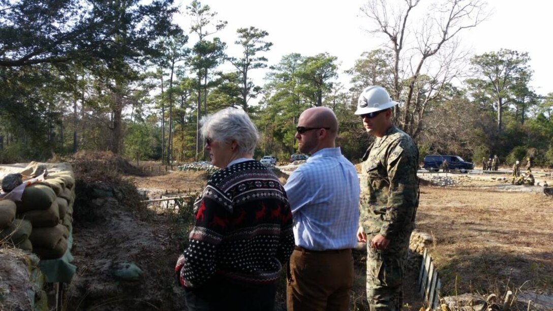 On December 16, 2014, Ryan Crumpler and Vickie Plunkett, both Professional Staff Members on the House Armed Services Committee, visited Marine Corps Engineer School in order to gather information regarding enlisted entry level training.  Here they are seen getting a brief from GySgt Cascell at the survivability training site.