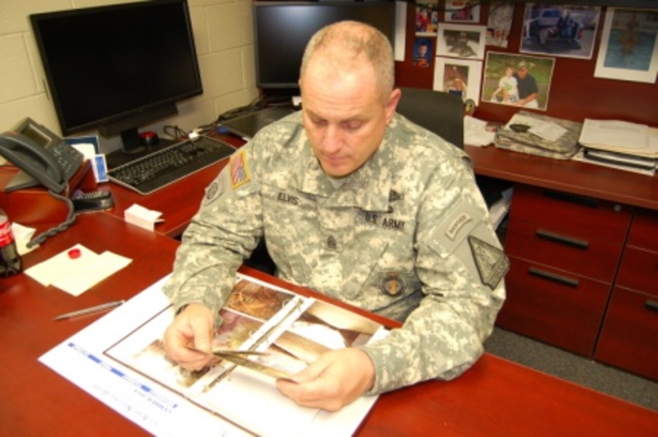 Command Sgt. Maj. Ronald Elvis, Recruiting and Retention Battalion Command sergeant major, South Carolina Army National Guard, looks at pictures from his deployment to Operation Just Cause in Panama in 1989,Courtesy photo